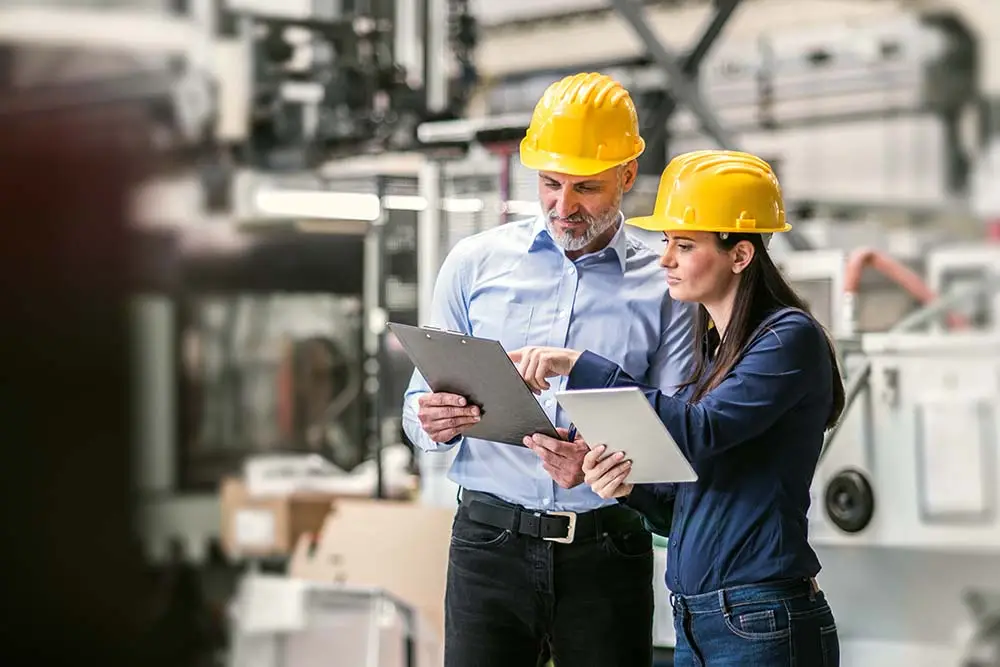 two workers checking statistics in manufacturing plant