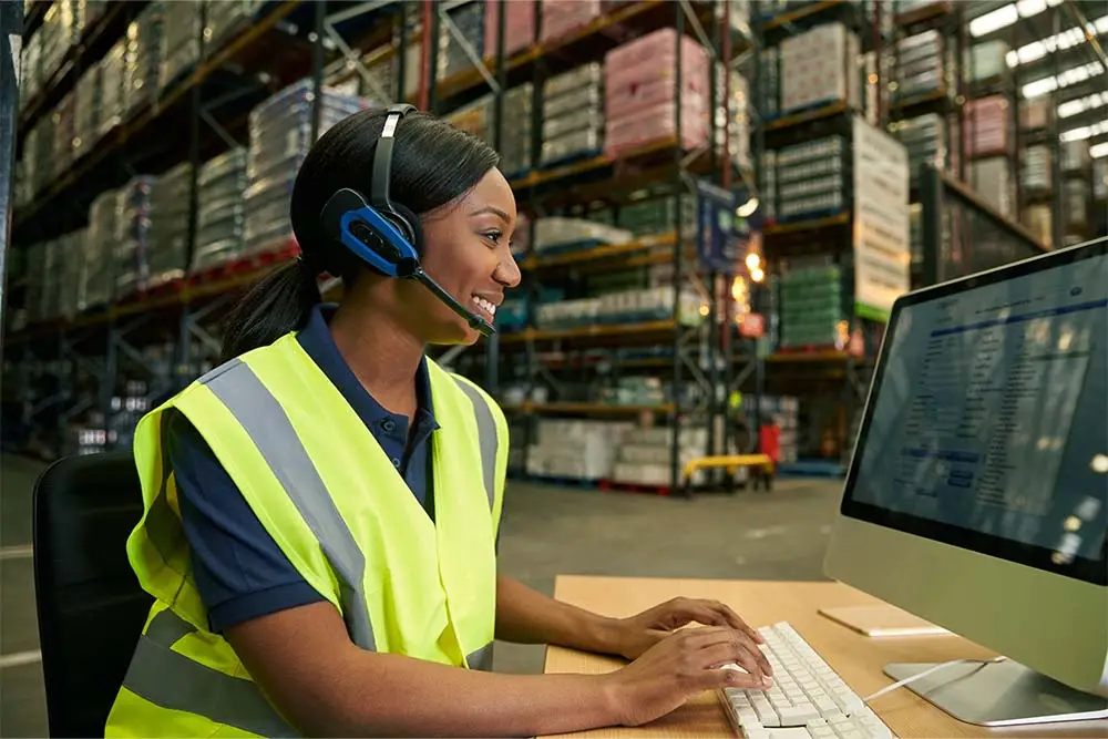 woman wearing an audio headset looking at a computer
