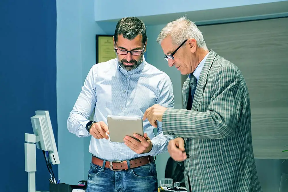 two men looking at a tablet