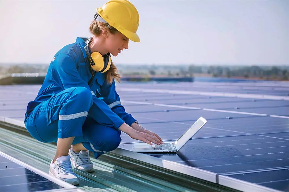female worker on roof examining solar panels